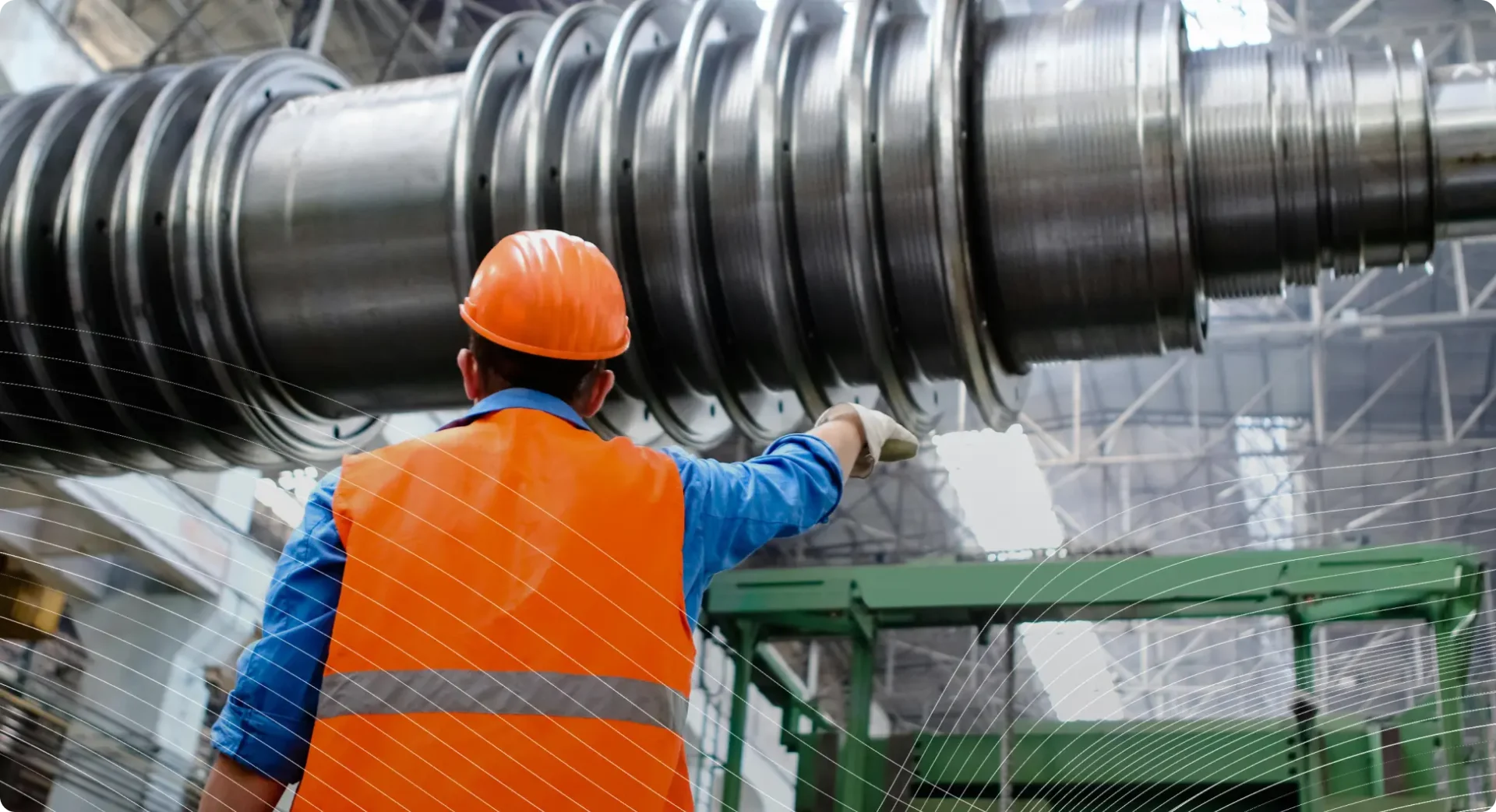 Worker in safety gear inspecting a large metal component in an industrial factory.